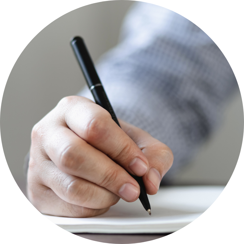 close up of a man's hand as he writes on a notepad with a black pen