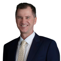 A head shot of Justin Oliver, wearing a suit and smiling at the camera.